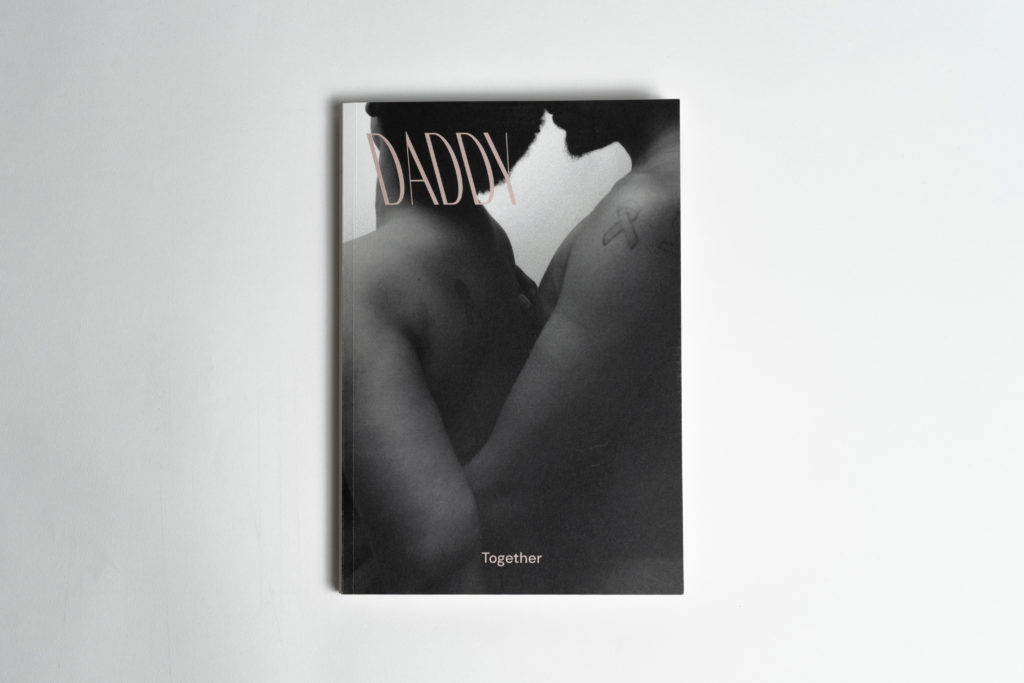 A minimalist photo of the cover of DADDY'S print issue TOGETHER, which features an intimate portrait of two people embracing